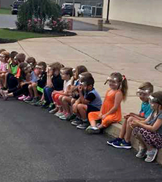 Row of students sitting on the edge of a sidewalk