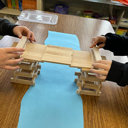 more students building a bridge out of popsicle sticks